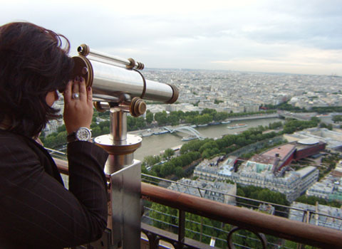W. Wassermann guckt vom Eiffelturm mit einem Fernrohr auf die Stadt